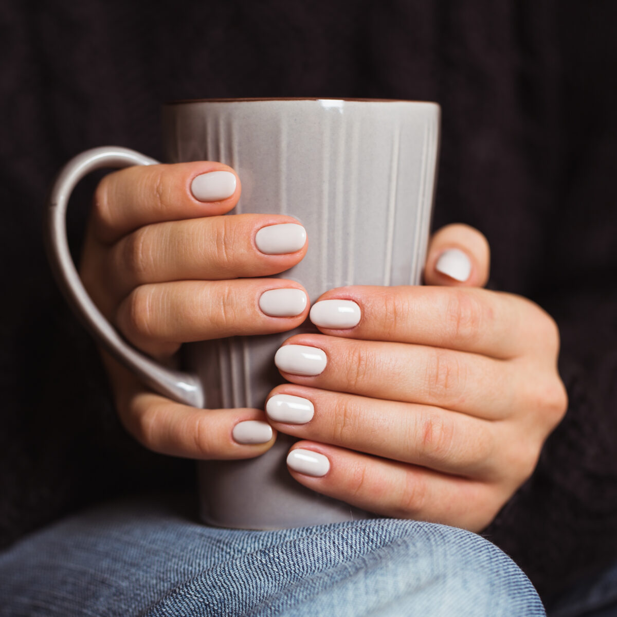 Woman with beautiful manicure holding a gray cup of tea