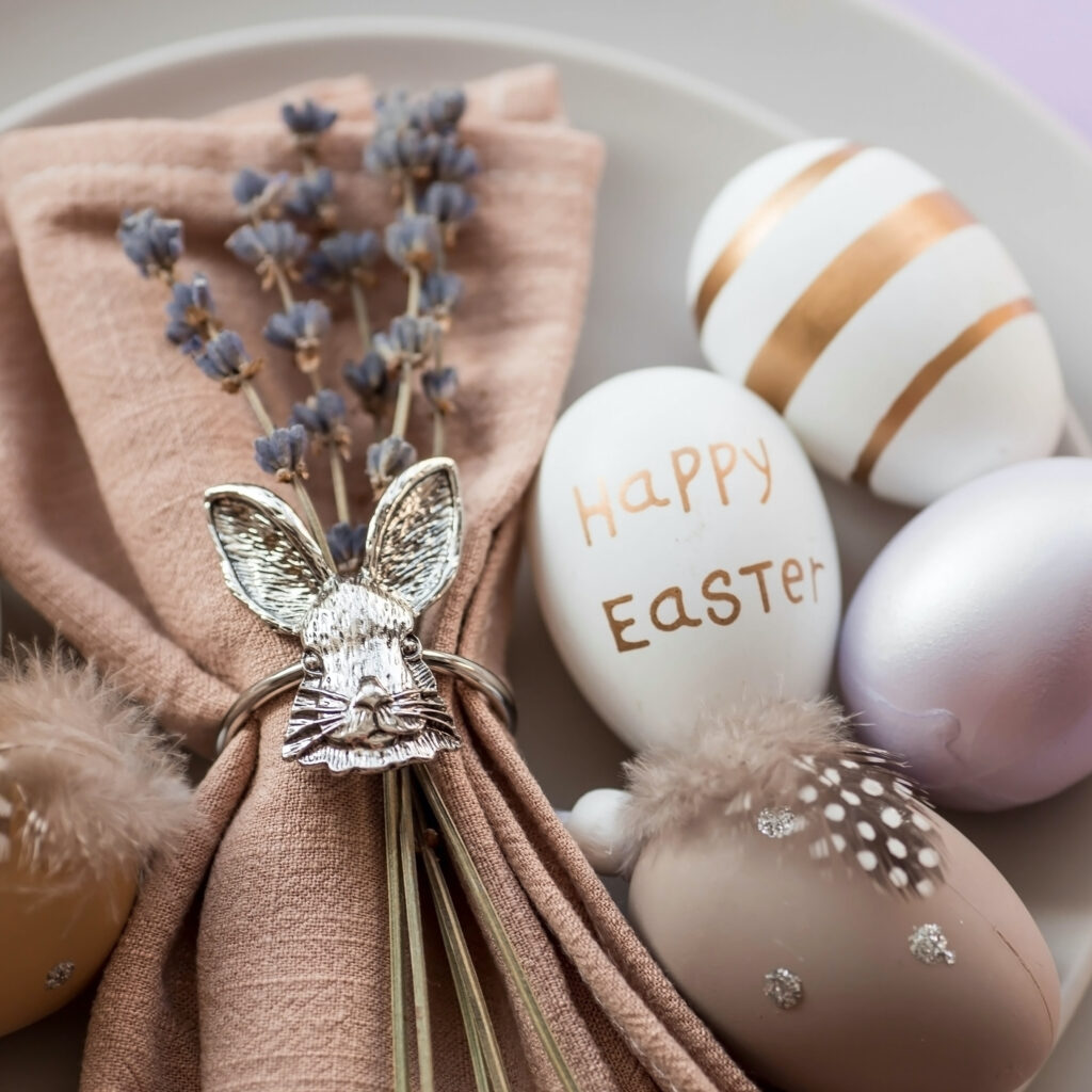 The concept of a happy, bright Easter holiday. Table setting. A plate with a rabbit on a napkin, lavender and Easter eggs on a fashionable background of 2022 is a veri pery. Top view.